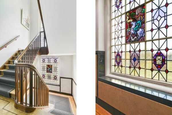 Trapopgang met houten leuning en kleurrijk glas-in-loodraam in een gebouw aan de Kleine Houtweg.